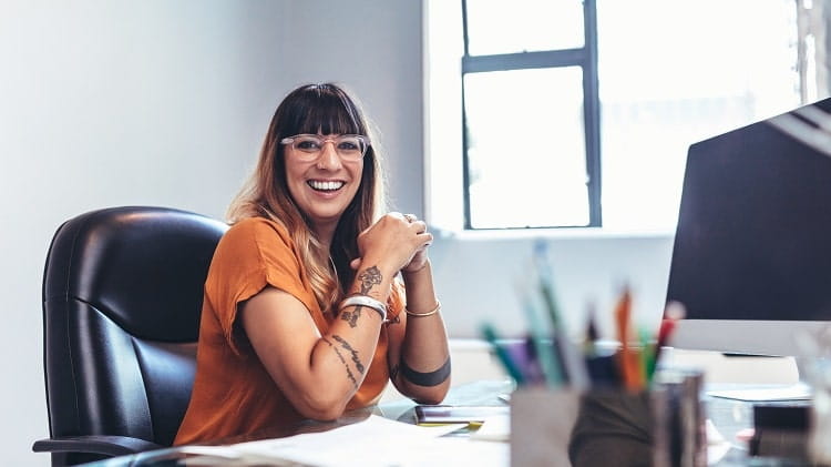 En kvinna sitter på sitt kontor och ler