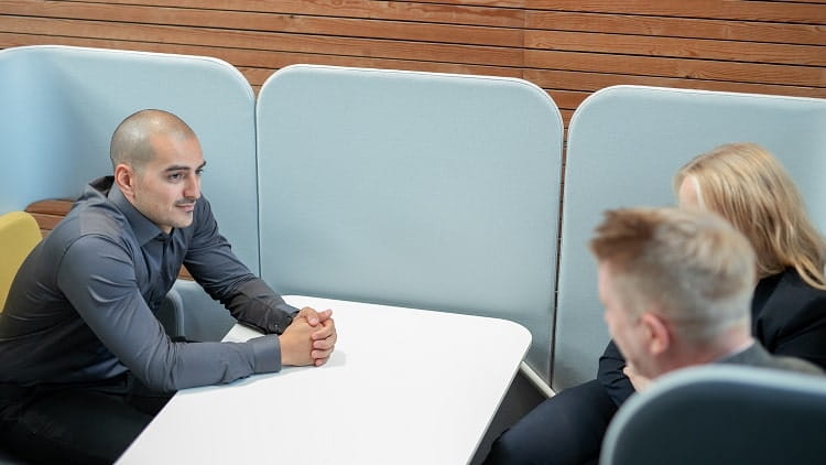 Tre personer har ett samtal kring ett bord på kontoret
